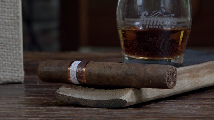cigar advisor #nowsmoking cigar review nestor miranda special selection rosado - setup shot of the cigar on a whiksy stave with a glass of spirits in the background