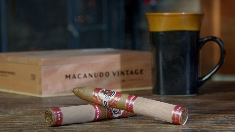 cigar advisor #nowsmoking cigar review - macanudo vintage 2010 setup shot of cigars with box and mug of coffee in the background