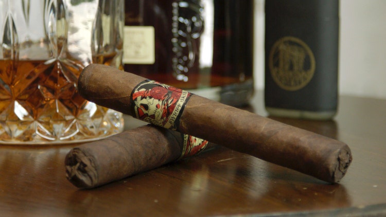 Drew Estate Deadwood Yummy Bitches Sweet Jane cigars set on a table with a drink pairing