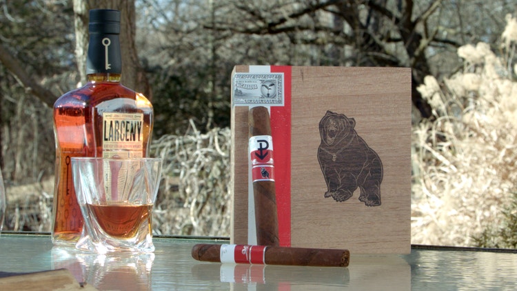 cigar advisor #nowsmoking cigar review powstanie wojtek 2021 - set up shot of cigars, one leaning against box, with a bottle of whiskey and whiskey glass