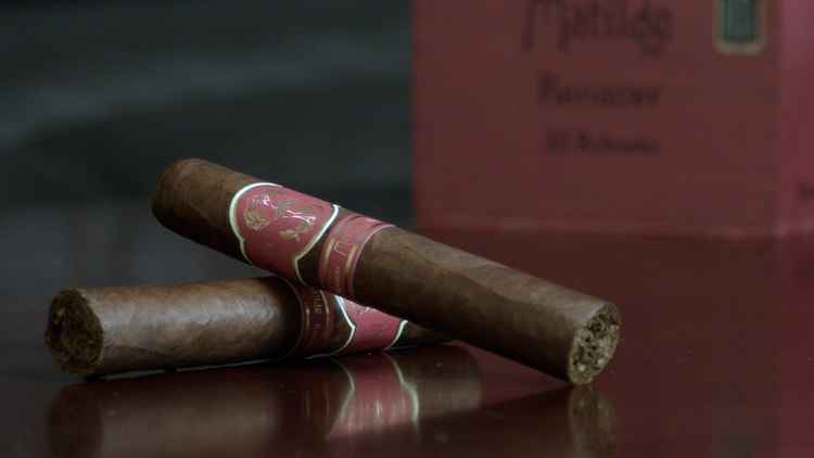 two matilde renacer robusto cigars on a table with the box as a backdrop