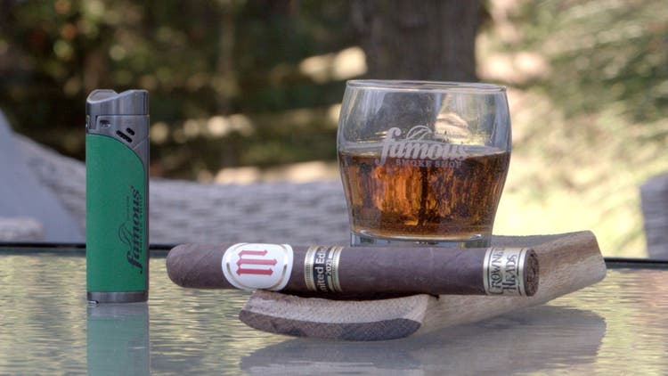 cigar advisor my weekend cigar crowned heads mil dias marranitos 2023 - setup shot of the cigar with a glass of spirits in the background