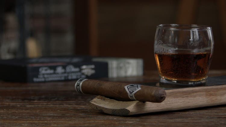 cigar advisor #nowsmoking cigar review todos las dias thick lonsdale "mas fuerte" - setup shot of cigar on whisky barrel stave with box and whisky in the background