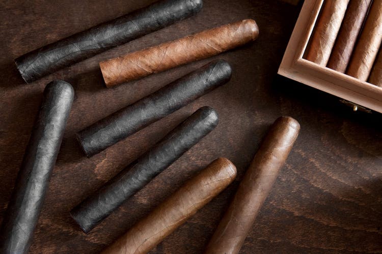 cigar advisor top 12 best-tasting maduro cigars - setup shot of dark cigar next to lighter cigars