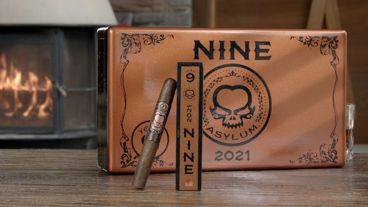 cigar advisor #nowsmoking review video of asylum nine 11/18 - shot of cigar next to box in front of fireplace