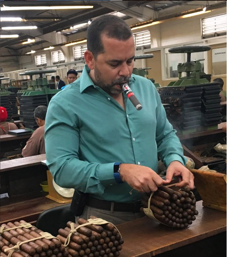 Yuri Guillen, Operations Manager of La Gloria Cubana Cigars Smokes a Cigar While Inspecting a Bundle