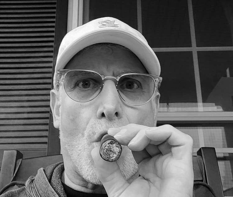 gary korb puffing on a cigar to write his review