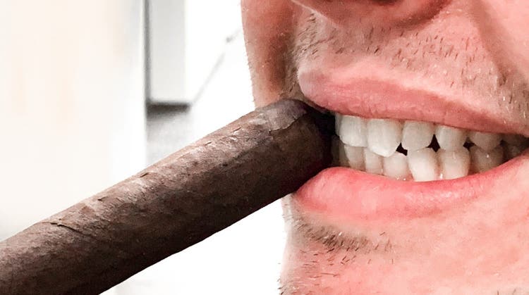 enjoying cigars for smokers with dentures biting off a pigtail cap on a cigar