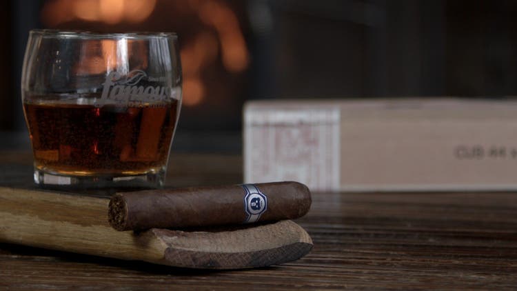 cigar advisor #nowsmoking cigar review warped el oso - shot of the cigar with whisky, box, and fireplace in the background