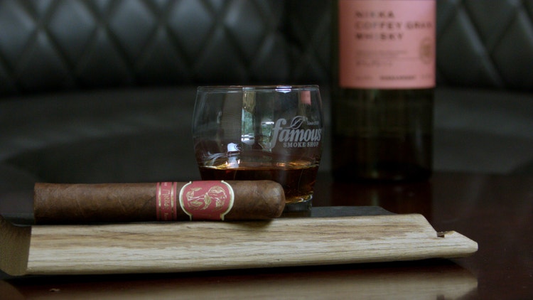 matilde renacer robusto cigar and famous smoke shop rocks glass on a wooden stave with a bottle of nikka coffee grain whisky cigar pairing