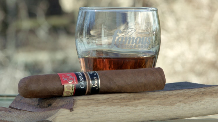 cigar advisor #nowsmoking cigar review e.p. carrillo retro 2021 - setup shot of cigar on a whiskey barrel stave in front of a whiskey glass