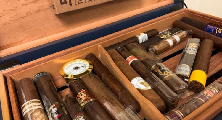 The inside of a humidor with a collection of cigars and hygrometer - temperature and humidity affect cigar freshness
