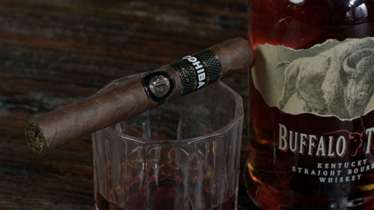 cigar advisor panel review of weller by cohiba 2022 - setup shot of cigar on whiskey glass with buffalo trace bottle behind