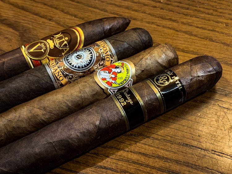 cigar advisor best medium bodied cigars - setup shot of oliva, perdomo, la gloria cubana, and rocky patel cigars on a table