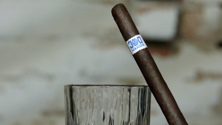 300 hands maduro lancero by southern draw leaning against whiskey glass