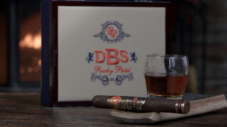 cigar advisor #nowsmoking cigar review rocky patel dbs - setup shot of the cigar with the box and a glass of whiskey in the background