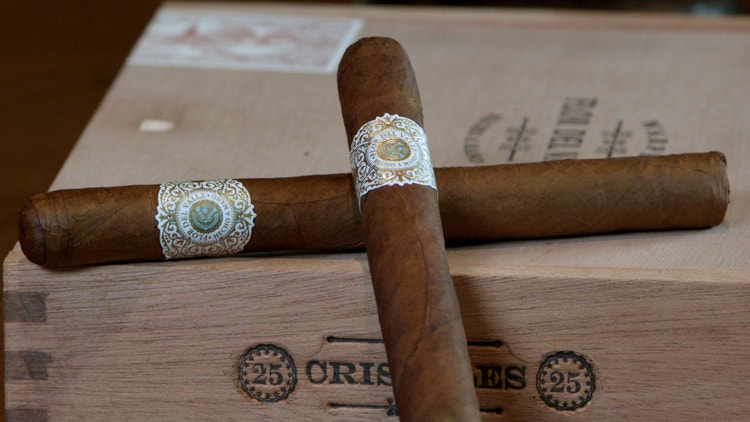 2 Warped Flor del Valle cigars are leaning against the cigar box in preparation for a cigar review
