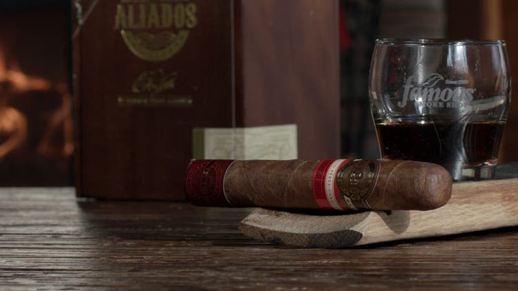 cigar advisor panel review video cuba aliados cabinet by e.p. carrillo - setup shot of cigar with whiskey, box, and fireplace in background