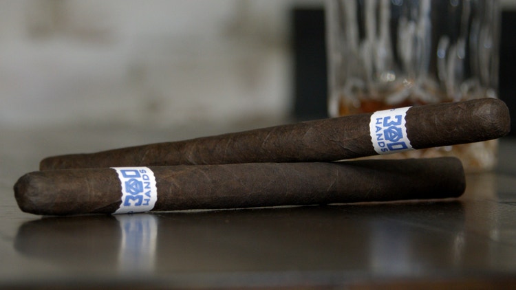 setup shot of two 300 hands maduro lancero cigars from the nowsmoking cigar review