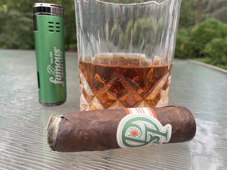 Cigar Advisor #nowsmoking cigar review part 2 cigar resting on table with cigar lighter and whiskey