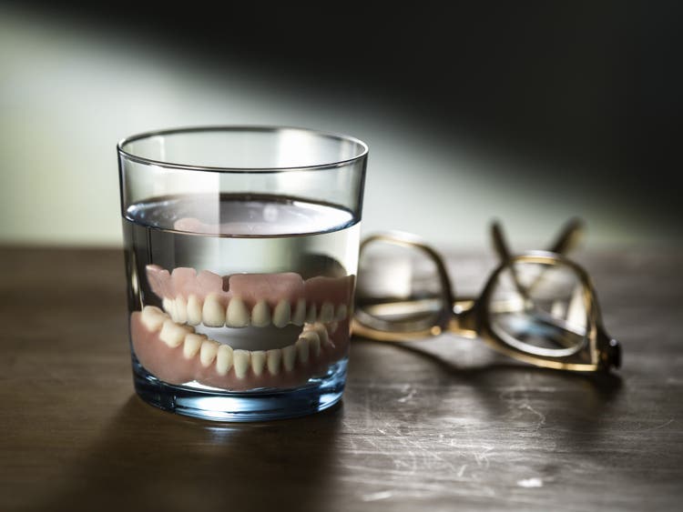 enjoying cigars for smokers with dentures cleaning teeth in a glass of water