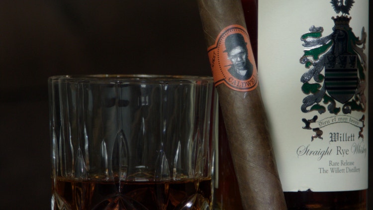 cigar advisor nowsmoking cigar review caldwell blind man's bluff nicaragua - cigar leaning against whiskey glass and bottle of spirits